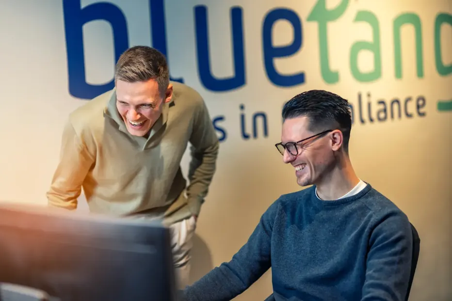 Twee Bluetang collega's overleggen achter een beeldscherm